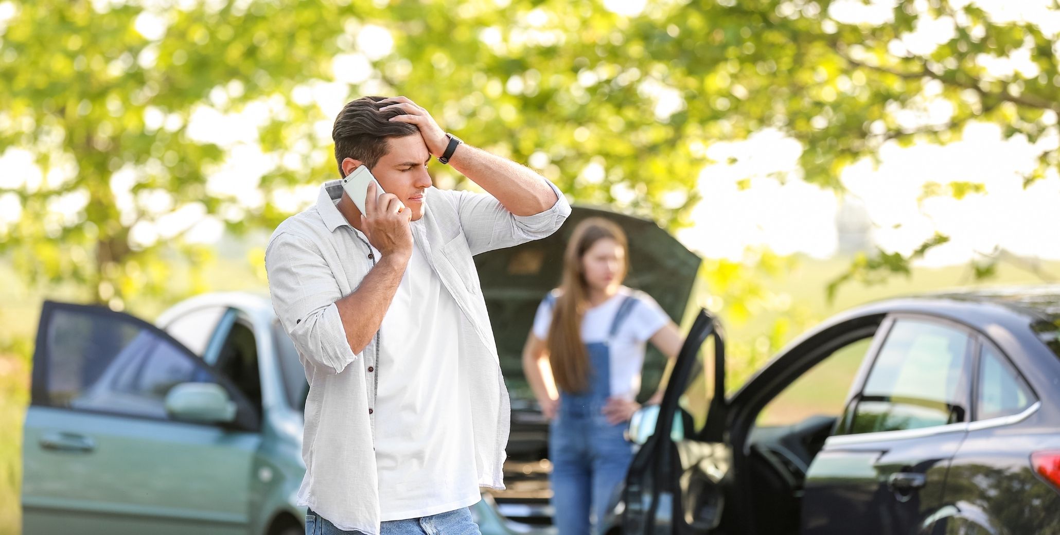 Two people inspecting car accident damage